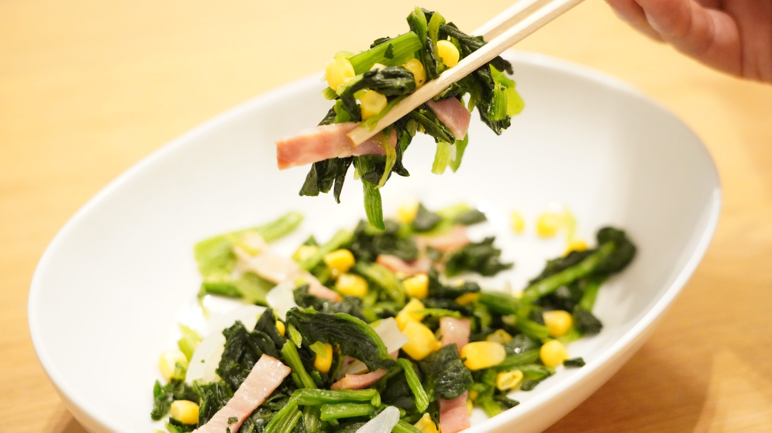 セブンイレブンのおすすめ冷凍食品「ベーコンほうれん草」を箸でつまんでいる写真