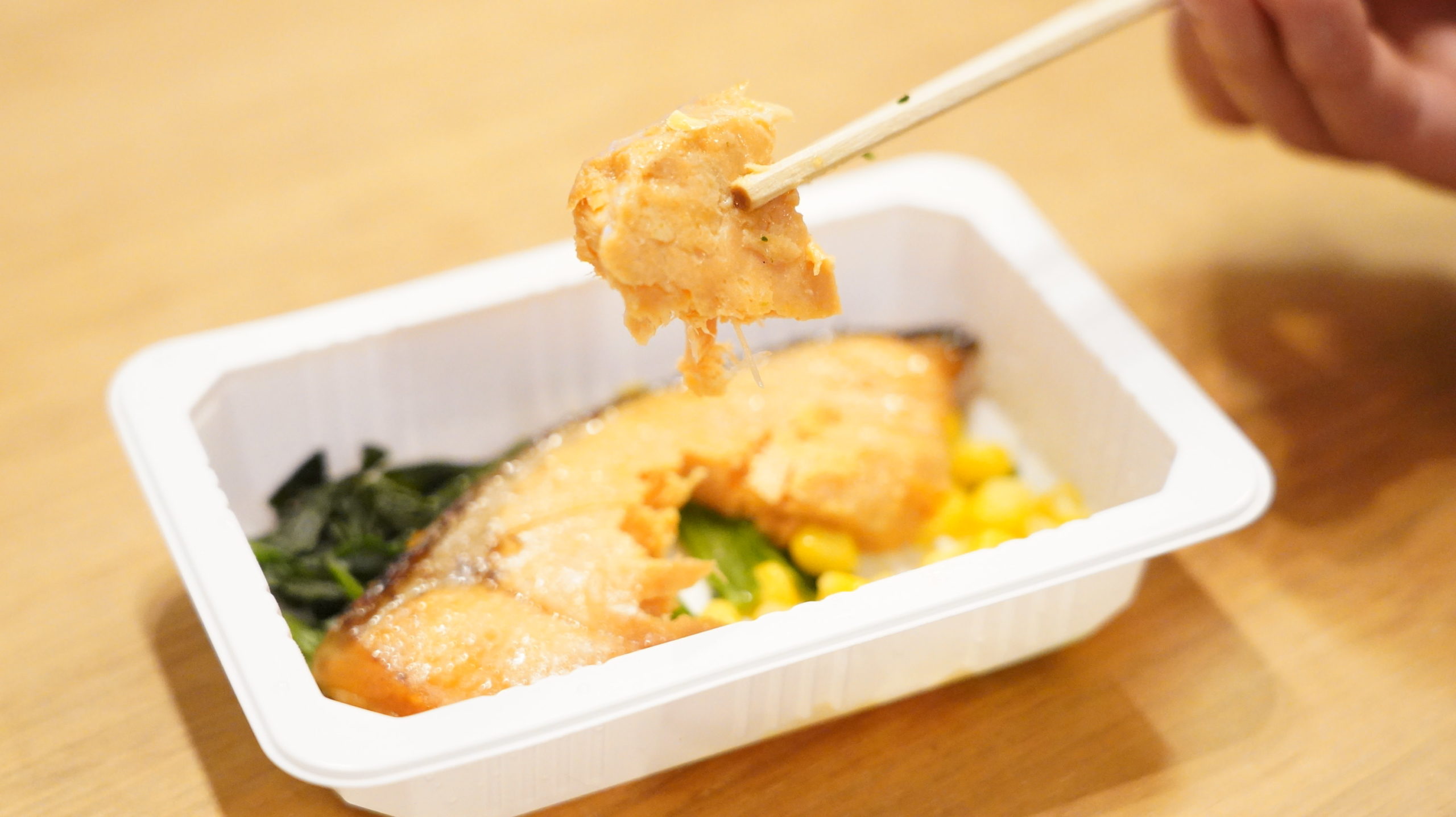セブンイレブンの冷凍食品「バター香る銀鮭の醤油焼」の銀鮭を箸でつまんでいる写真