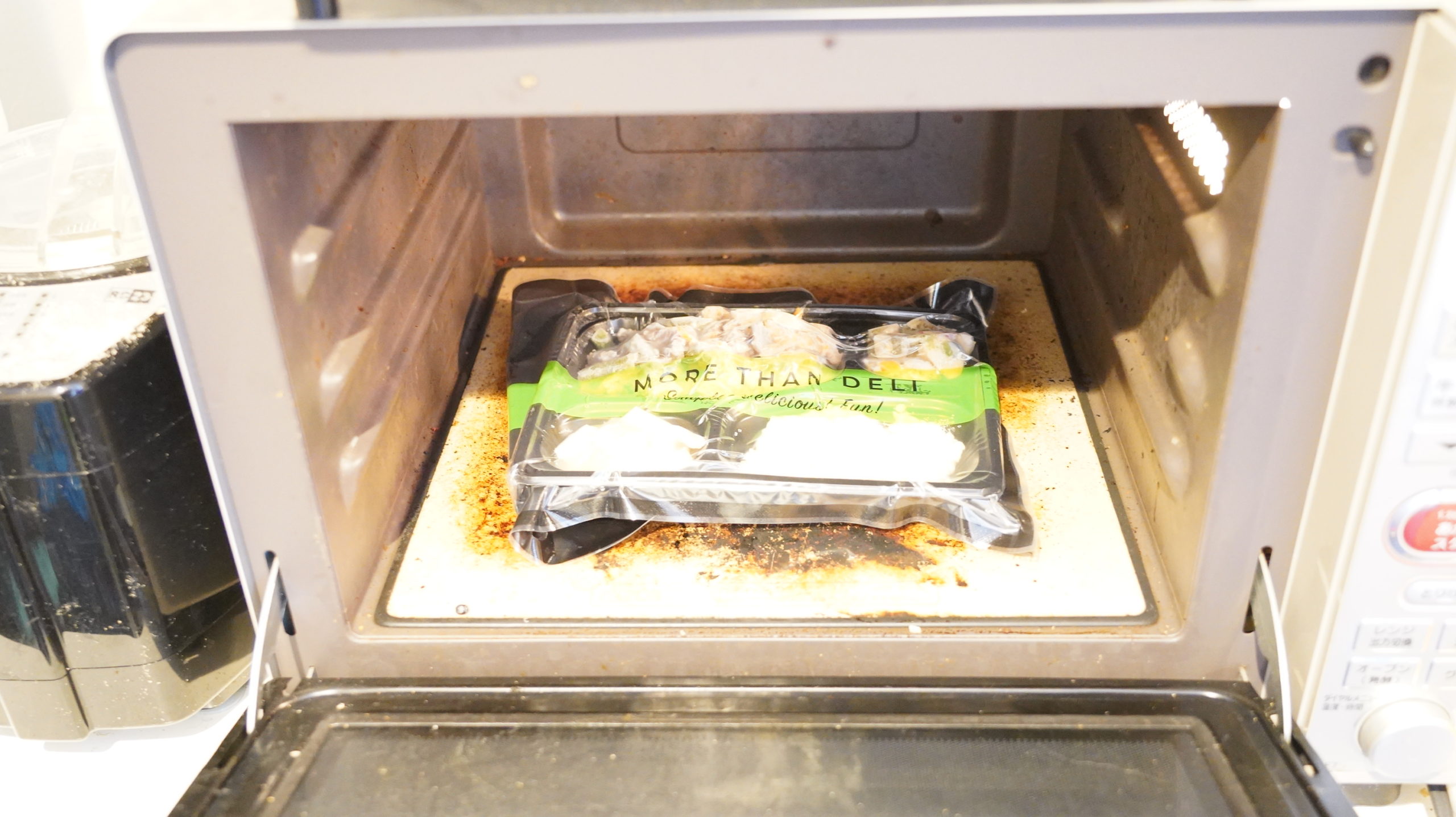 More than Deli（モアザンデリ）の冷凍弁当「鶏肉と野菜の黒酢あんかけ」を電子レンジで加熱している写真