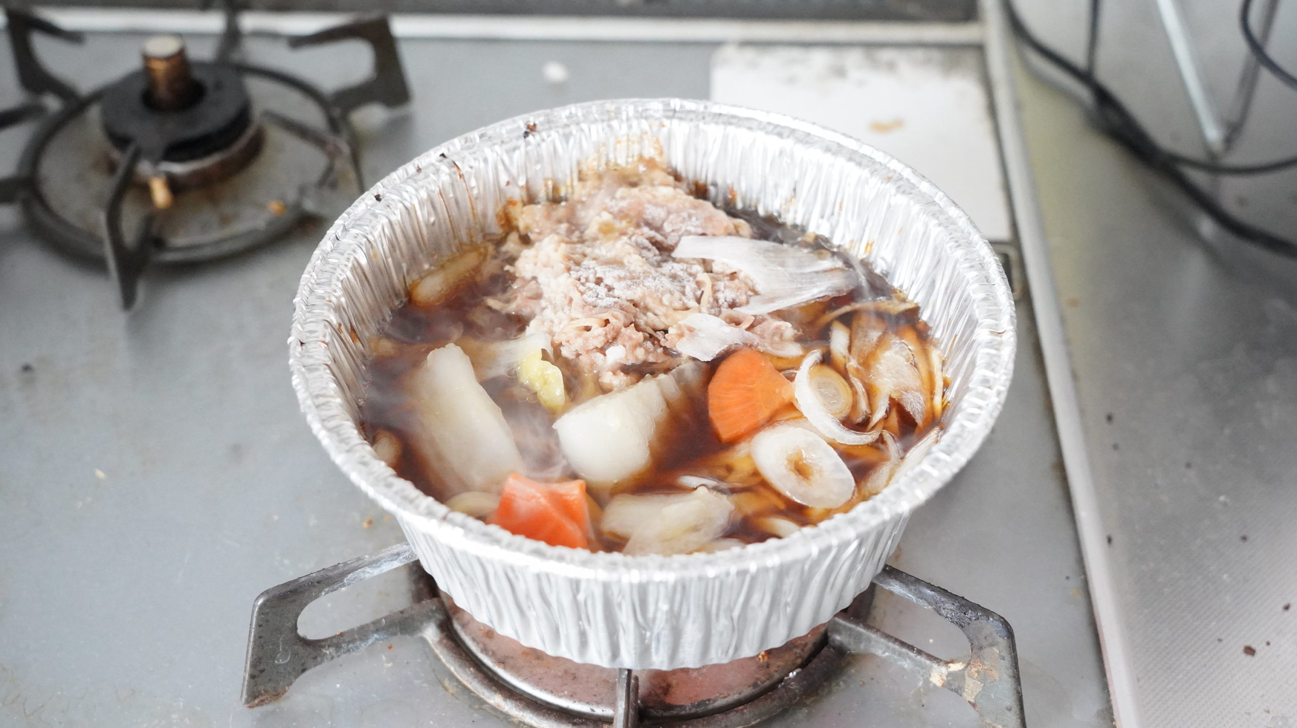 ファミリーマートの冷凍食品「牛肉の旨味！牛すき焼き鍋（うどん入り）」をガスコンロで加熱し終わった写真