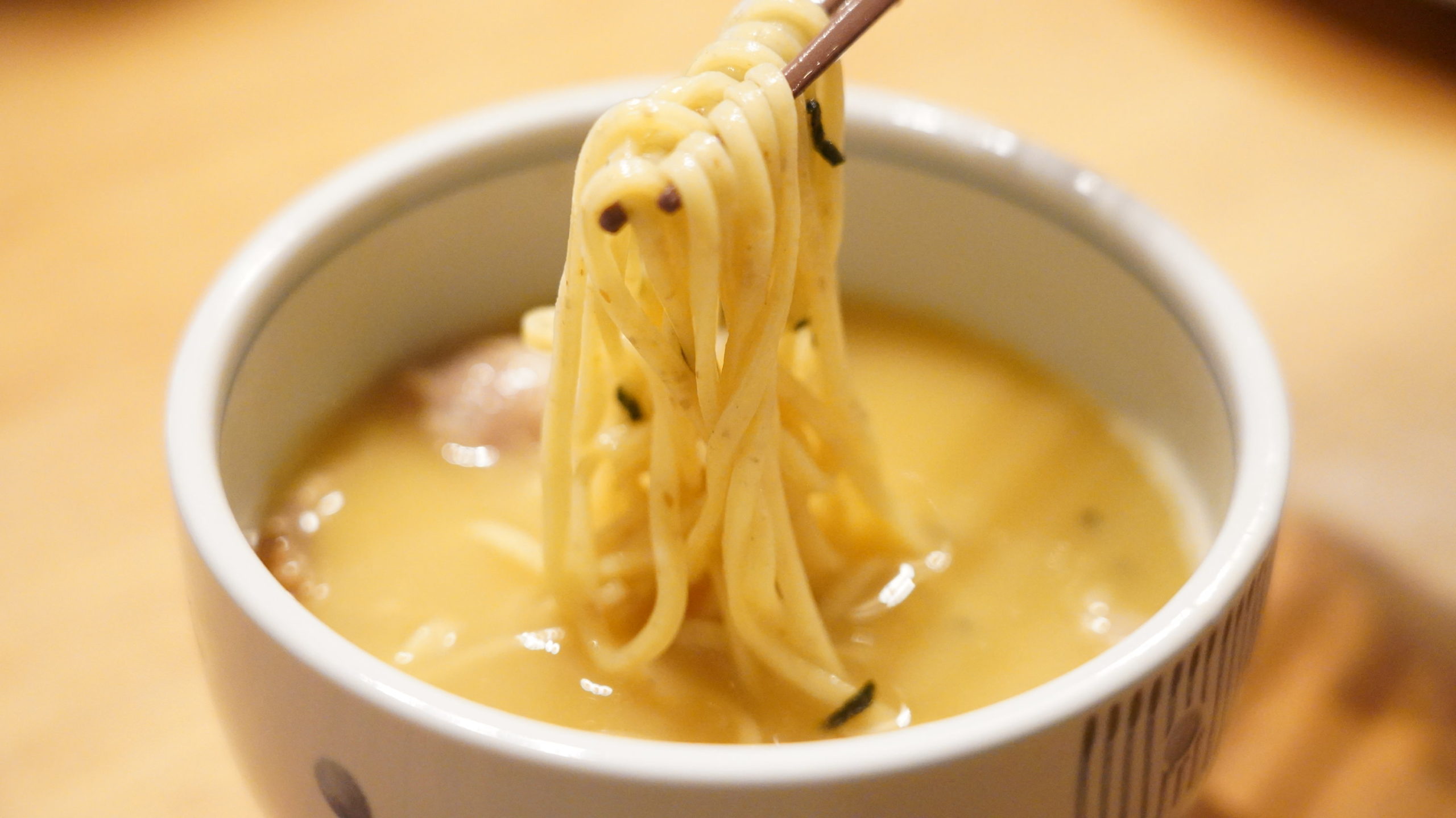 「ラーメンにっこう」のお取り寄せオンライン通販「柚子白湯つけ麺」の麺を箸でつまんでいる写真