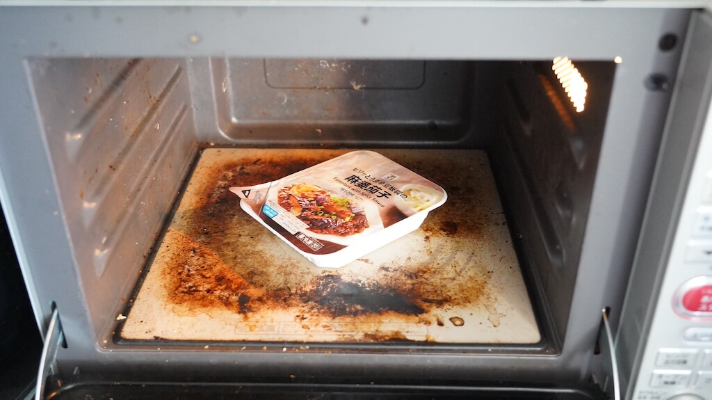セブンイレブンの冷凍食品「ピリッとうま辛豆板醤の麻婆茄子」を電子レンジで加熱している写真