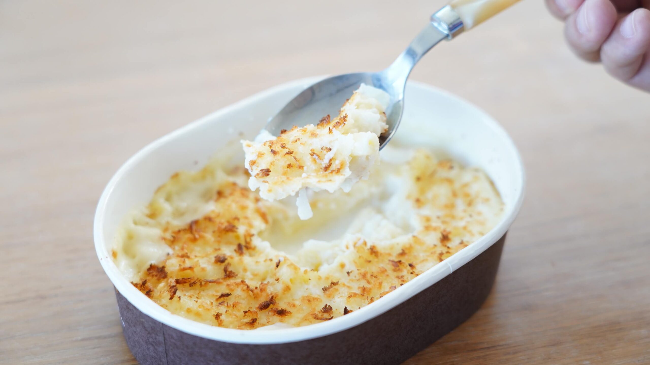 セブンイレブンの冷凍食品「チーズの香り広がる・マカロニグラタン」をスプーンですくっている写真