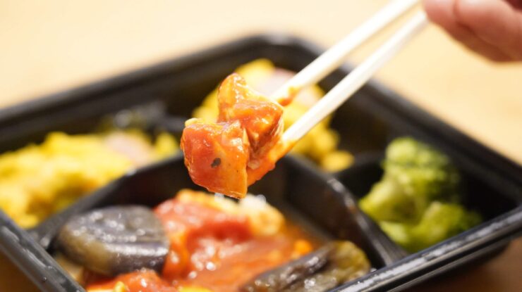 ライザップ（RIZAP）で食事制限してダイエットする際に使う宅食用ボディメイク冷凍弁当「サポートミール」（健康食品）の「チキンのトマトソースがけ」を箸でつまんでいる写真