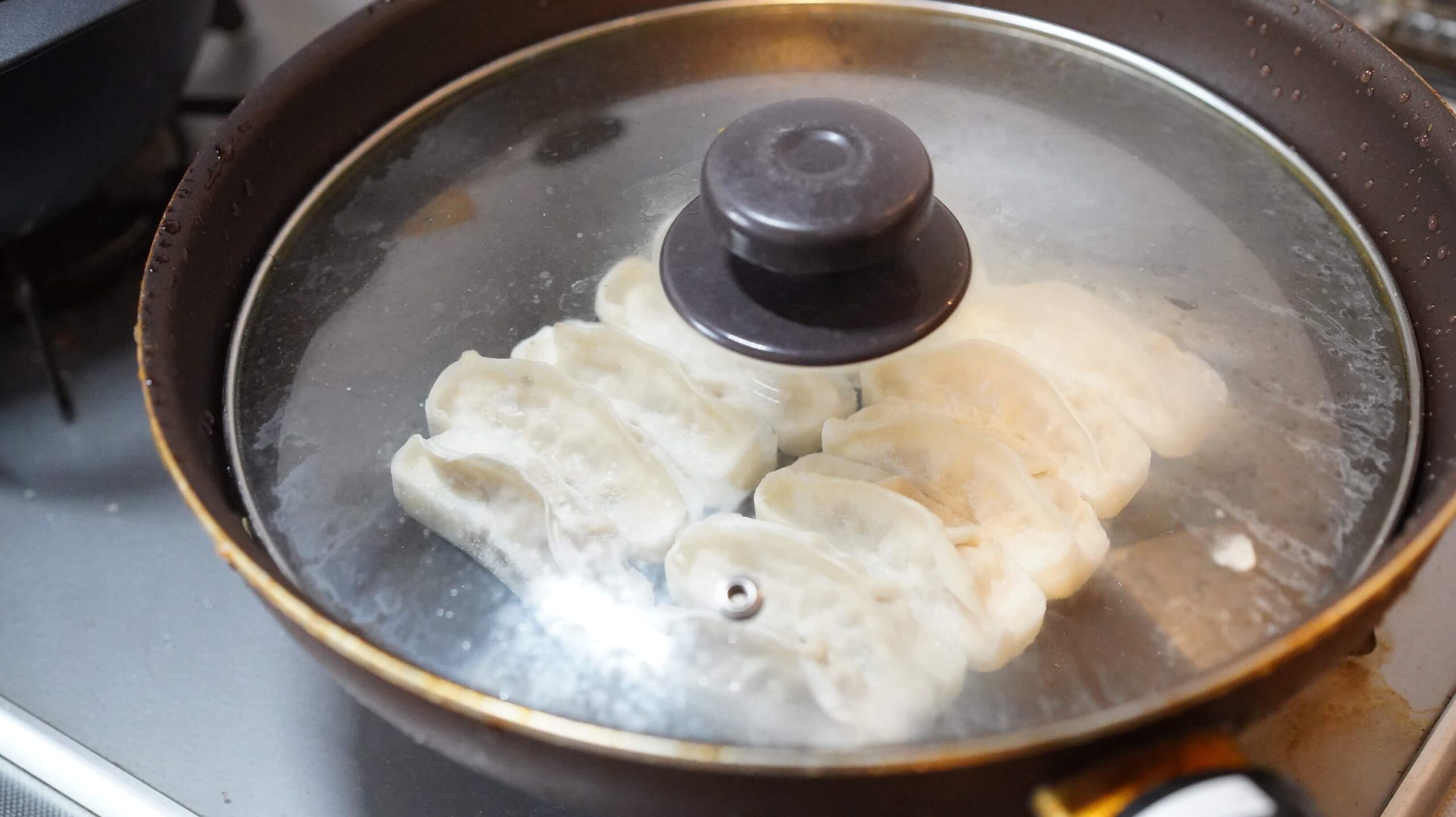 味の素の冷凍食品「生姜好きのためのギョーザ」をフライパンで焼いている写真