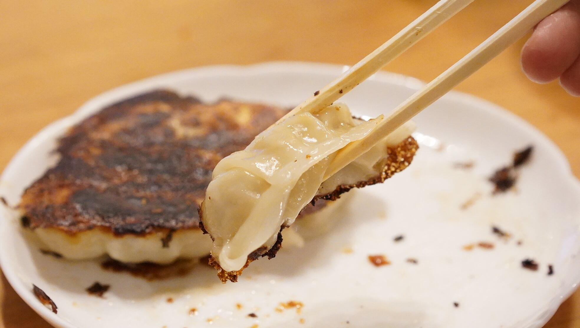 味の素の冷凍食品「生姜好きのためのギョーザ」を箸でつまんでいる写真