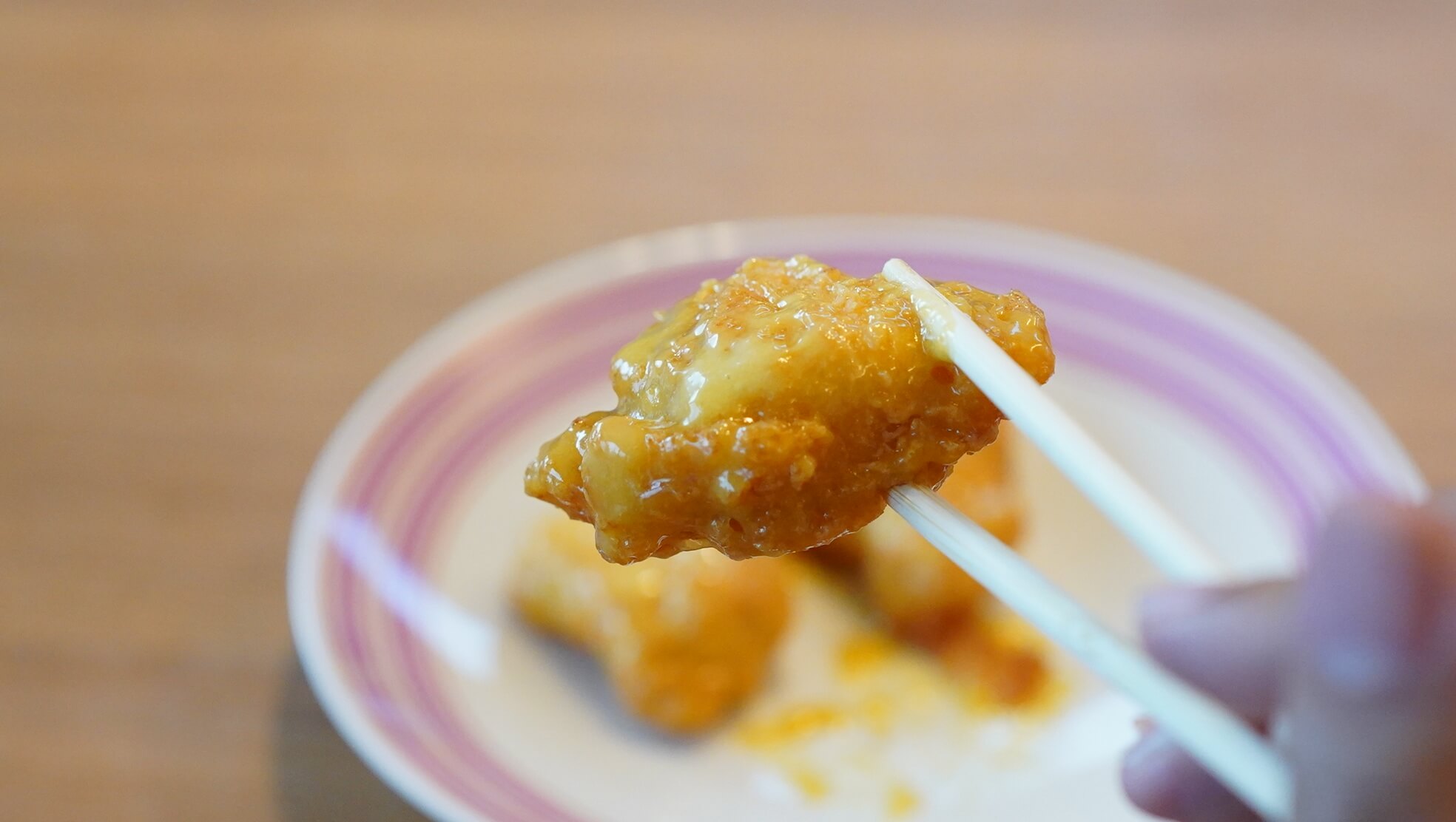 ニチレイの冷凍食品「ハニーマスタードチキン」を箸で持ち上げている写真