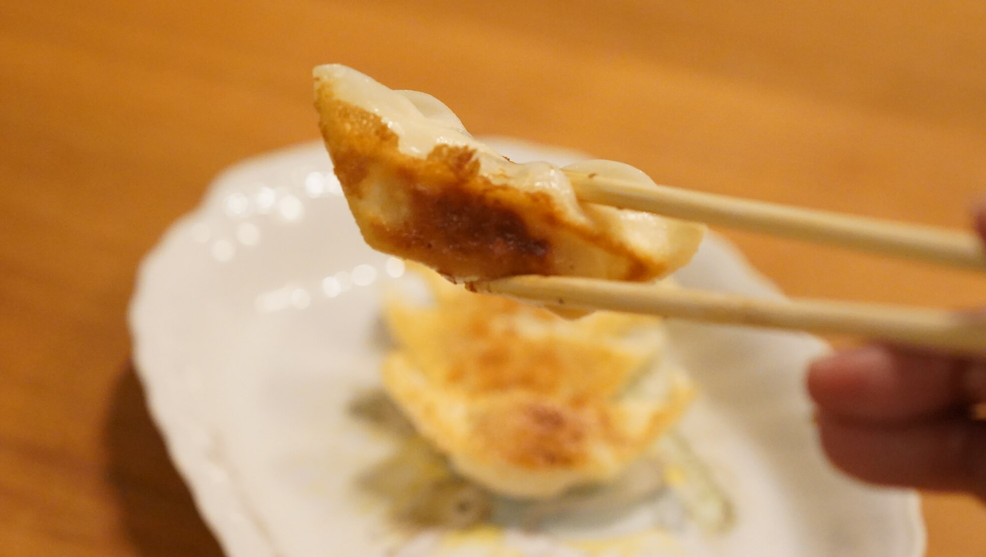 味の素のアスリート向け冷凍餃子「エナジーギョーザ」を箸でつまんでいる写真
