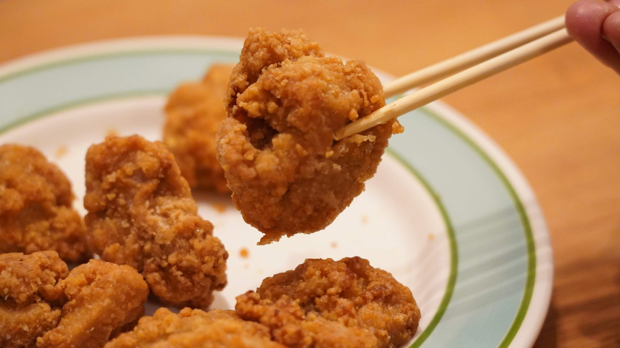 イオン・トップバリュ(TOPVALU)の冷凍食品「若鶏の竜田揚げ」を箸でつまんでいる写真