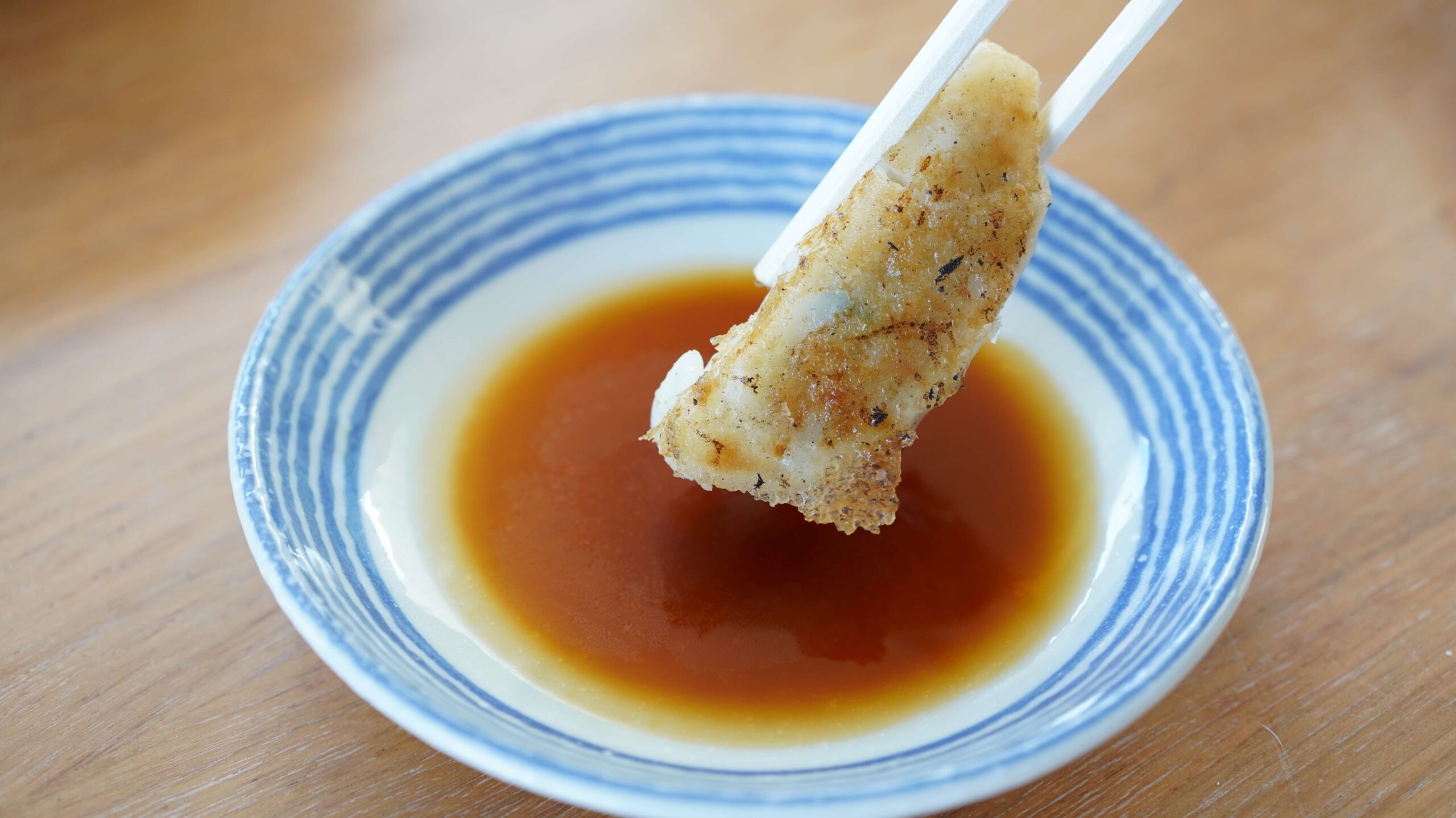 イオン・トップバリュおすすめ冷凍食品「ギョーザ」を箸で持ち上げている写真