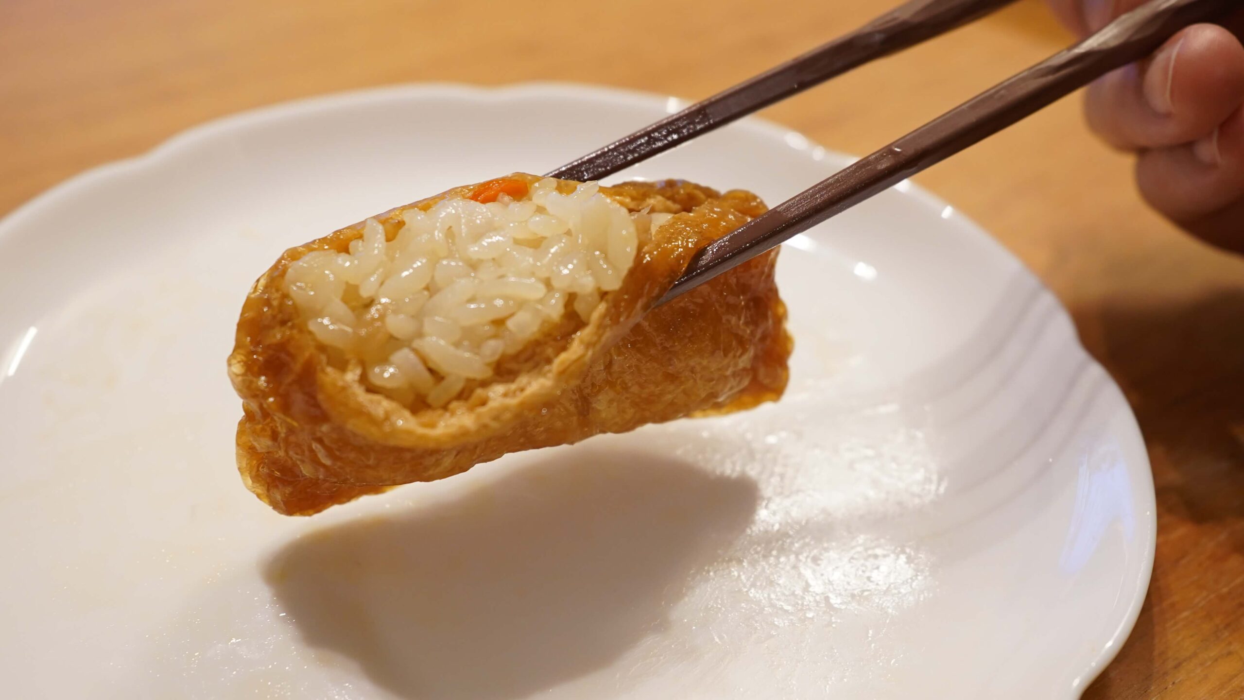 「ごはんの里」の冷凍食品「五目いなり寿司」を箸で持ち上げている写真