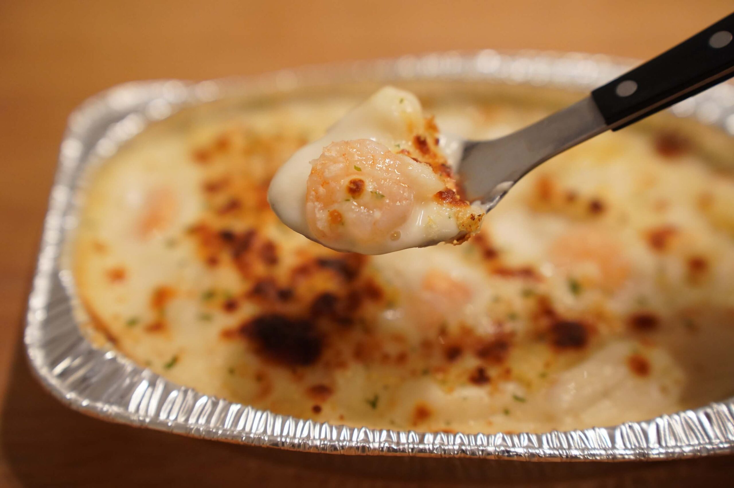 生協宅配の「十勝産チーズが香る海老グラタン」をスプーンですくっている写真