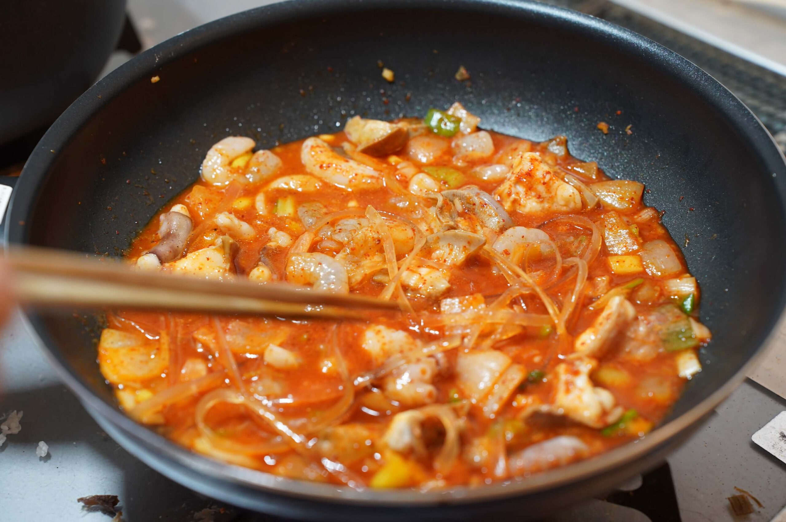韓国・釜山の伝統料理「ナッコプセ」をフライパンで調理している写真