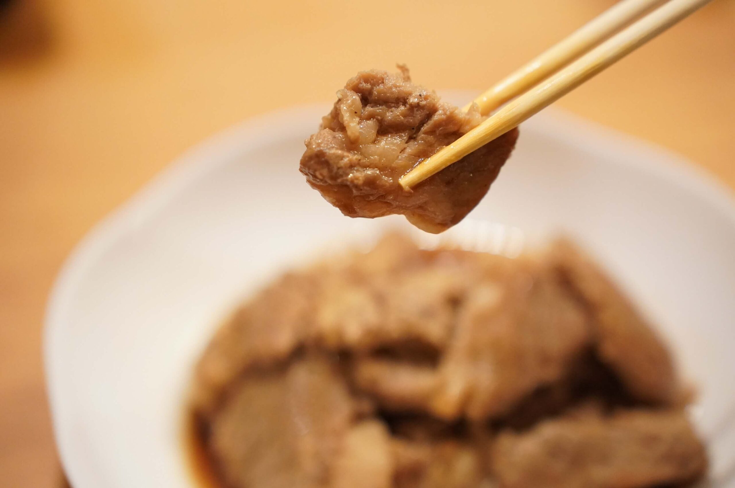 韓国料理「釜山熟成豚カルビ」を箸で持ち上げた写真