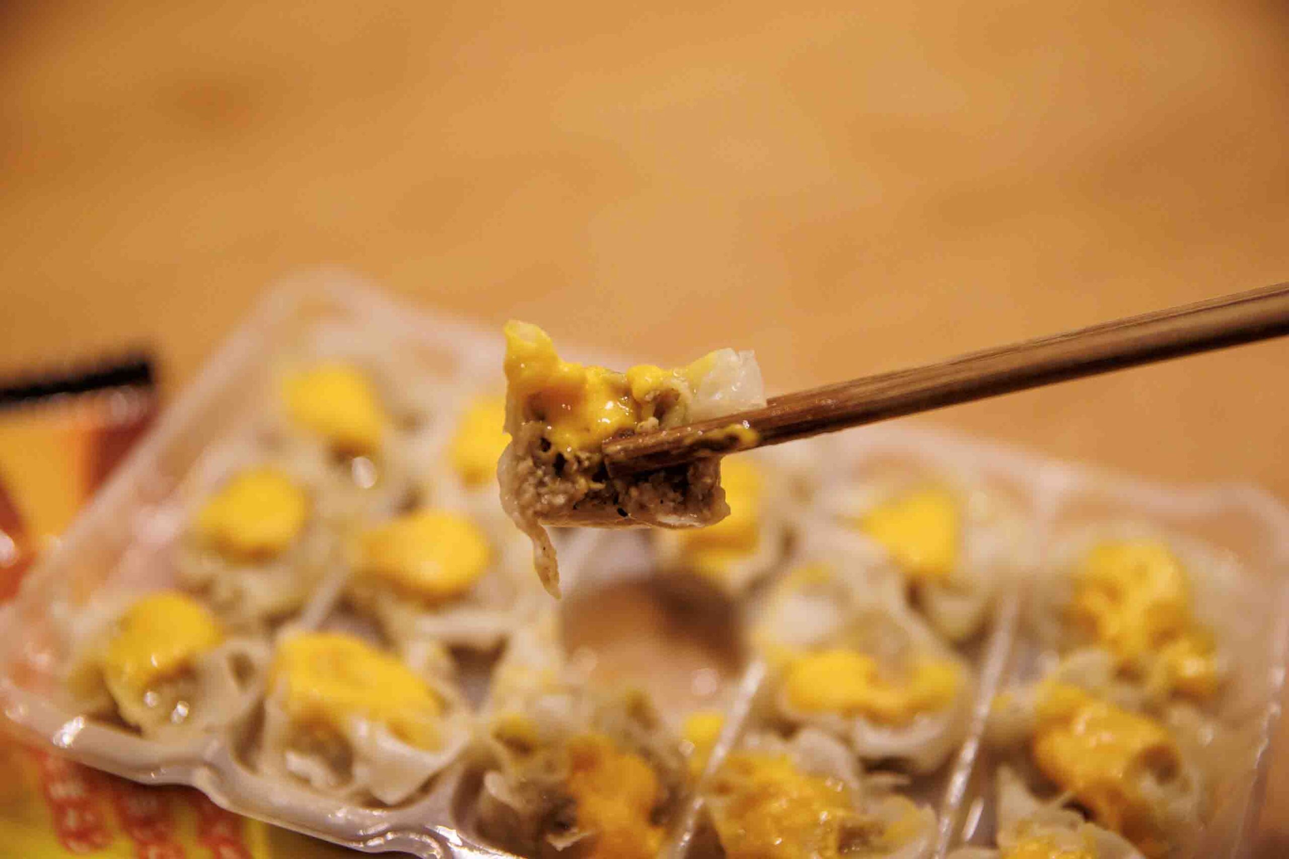 味の素の冷凍食品「濃厚チーズ焼売」を箸でつまんいる写真