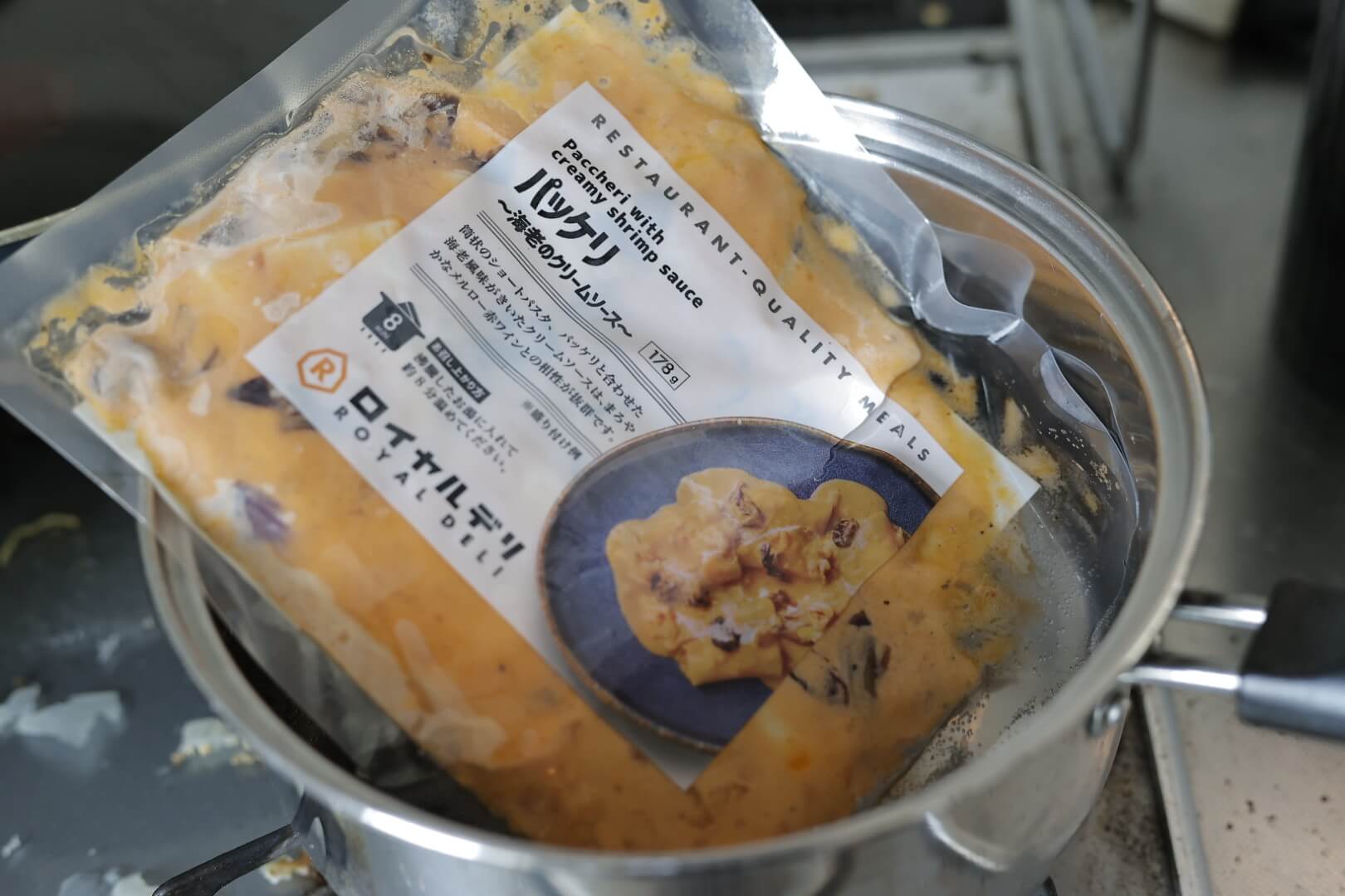 ロイヤルデリの冷凍食品「パッケリ　海老のクリームソース」を湯煎で加熱している写真